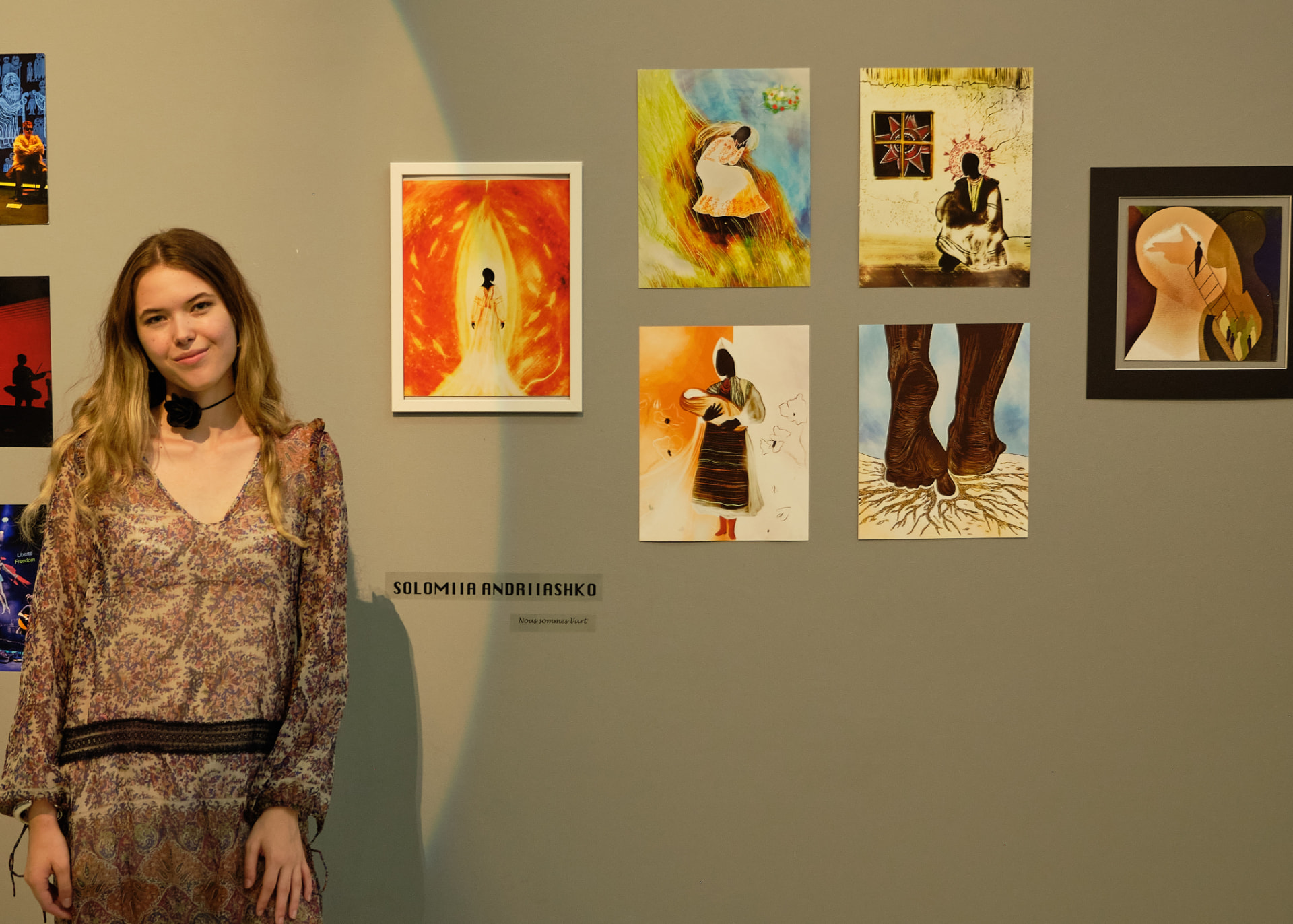 Solomiia beside her works at the exhibition
